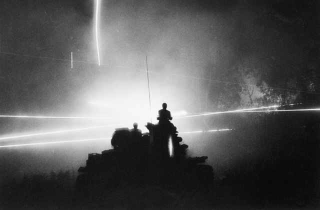 Soldiers of the U.S. 11th Armored Cavalry Regiment are silhouetted atop their tank by the glare of tracer bullets in Cambodia, July 6, 1970. In an exercise known as Mad Minute, they spray the area around them, possibly infiltrated by enemy patrols, before they move on. (AP Photo/Henri Huet)